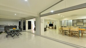 A modern kitchen with a dining area, a TV, and a large window.