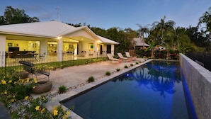 A modern house with a swimming pool, outdoor seating, and a well-maintained garden.