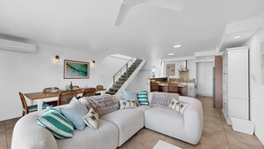 A modern living room with a sectional sofa, dining area, kitchen, and staircase. - Noosa Sound, waterfront, amazing value (NOOSA HEADS)