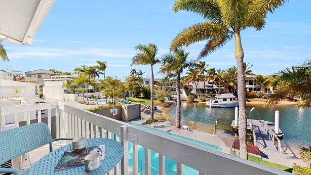 A balcony with a pool, overlooking a marina with boats and palm trees. - Noosa Sound, waterfront, amazing value (NOOSA HEADS)
