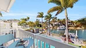 A balcony with a pool, overlooking a marina with boats and palm trees. - Noosa Sound, waterfront, amazing value (NOOSA HEADS)