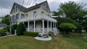 A two-story house with a porch, surrounded by a well-maintained lawn and various plants.