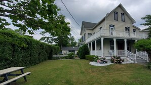 A two-story house with a porch, a small garden, and a white picket fence.