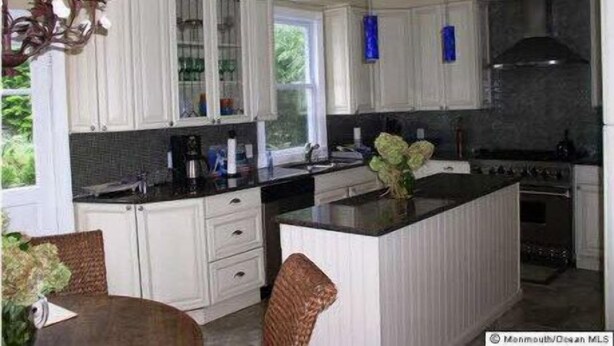 A modern kitchen with white cabinetry, a central island, and a dining area with a table and chairs.