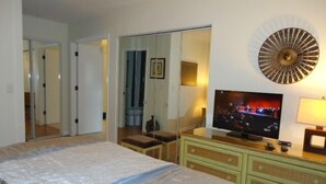 Ett hotellrum med en säng, en tv, en spegel och en byrå.