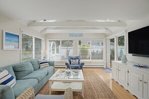 A living room with a sofa, armchair, coffee table, and a TV.