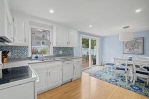 A modern kitchen with white cabinets, a black stove, and a tiled backsplash.