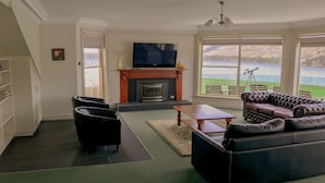 A living room with a fireplace, a television, and a view of a lake.