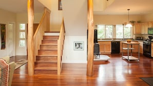 Un interior amplio con una escalera de madera, una cocina y un comedor.