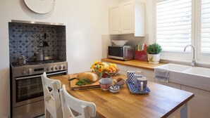 A modern kitchen with a stove, oven, microwave, and a window with blinds. - THE WHITE HOUSE luxury villa embedded in history (Penola)