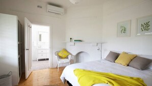 A bedroom with a bed, a fireplace, a chair, and a shelf with books. - THE WHITE HOUSE luxury villa embedded in history (Penola)