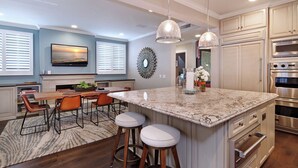 A modern kitchen with a large island, stainless steel appliances, and a dining area with a view of the sunset. - Luxury beach home with outside fireplace and dining, 10 minute walk to beach  (Newport Beach)