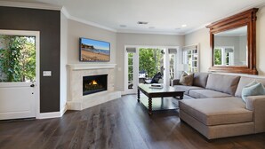 A living room with a fireplace, a sofa, and a coffee table. - Luxury beach home with outside fireplace and dining, 10 minute walk to beach  (Newport Beach)