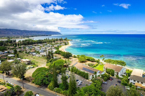 A coastal town with a beach, residential areas, and a large building with solar panels.