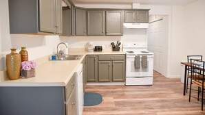 A kitchen with a white stove, a sink, and cabinets. - Relax & Feel At Home During Your Pittsburgh Stay (Pittsburgh)