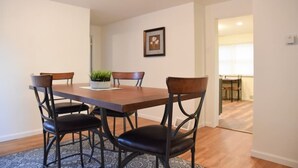 A dining area with a wooden table and four chairs, a potted plant, and a framed picture on the wall. - Relax & Feel At Home During Your Pittsburgh Stay (Pittsburgh)