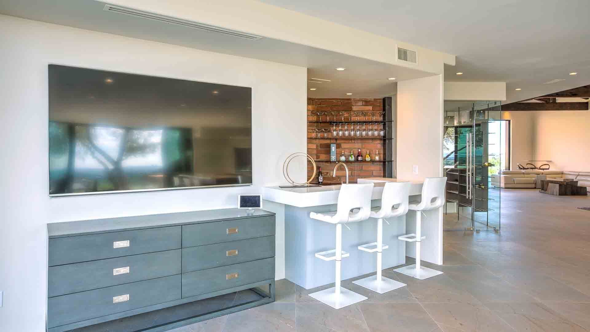 Une cuisine moderne dotée d’un grand îlot central, de tabourets de bar et d’un meuble à vin.