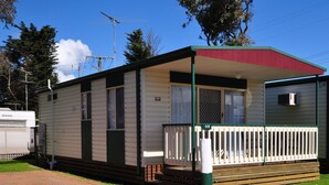 A mobile home with a porch and a small deck, surrounded by trees and a clear sky. - Dylene Caravan Park - 2 Br Family Cabin With Air (Portarlington)