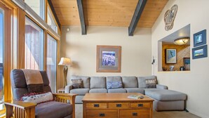 A cozy living room with a sofa, a wooden coffee table, and a lamp. - Walk to Gondolas! Heated Pool & Hot Tubs - Perfect for 2 couples & 2-4 singles or kids (Steamboat Springs)