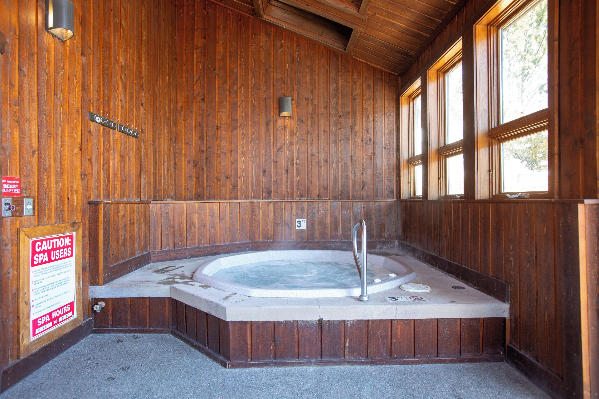 Een houten spa-ruimte met een bubbelbad, houten wanden en een raam.