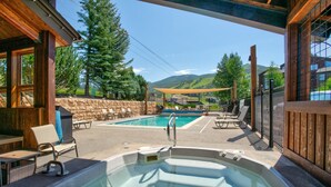 A hot tub area with a pool, outdoor seating, and a stone wall. - Walk to Gondolas! Heated Pool & Hot Tubs - Perfect for 2 couples & 2-4 singles or kids (Steamboat Springs)