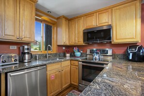 A modern kitchen with wooden cabinets, stainless steel appliances, and a granite countertop.