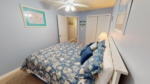 A bedroom with a bed, a ceiling fan, and a door leading to another room. - Ocean View Condo w/ Private Balcony, Easy Beach Access (Tybee Island)