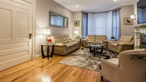A living room with a sofa set, two armchairs, a coffee table, and a TV. - UltraLuxe Apt in Boston Brownstone in Prime Area (Brookline)