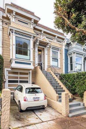 A residential building with a garage, a staircase, and a parked car.