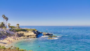 Una playa costera con una torre de salvavidas, acantilados rocosos y aguas azul turquesa.