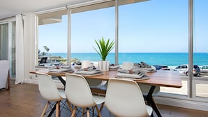 Un comedor con vista al océano, un ventilador de techo y una planta en maceta.