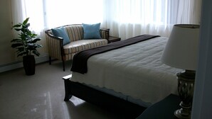 Een hotelkamer met een bed, een stoel, een lamp en een plant in een pot.