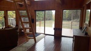 Un interior de madera con un amplio ventanal corredero que da a una terraza exterior.