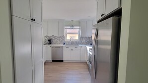 A modern kitchen with white cabinets, a stainless steel refrigerator, and a dishwasher. - Treasure Island Escape is Calling... Many Family Friendly amenities for Fun! (Treasure Island)