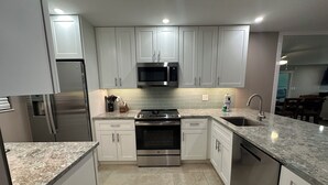 A modern kitchen with white cabinets, stainless steel appliances, and a granite countertop. - New Listing! Ground floor, easy access to the pool and beach! Siesta Dunes 2-104 (Siesta Key)