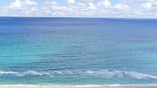 Een strand met helderblauw water en een zandstrand.