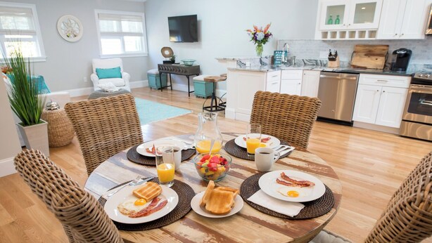 A dining area with a round wooden table set for breakfast, surrounded by wicker chairs. - Spacious and Updated 2 Bedroom Condo in the Heart of Newport (Newport)