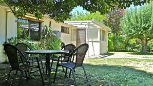 An outdoor seating area with a table and chairs, a covered structure, and a grassy lawn with trees. - ABBEVILLE IN BRIGHT: Bright (Bright)