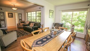 A dining area with a wooden table, chairs, and a patterned runner. There is a leather sofa and a chair with a lamp in the background. - ABBEVILLE IN BRIGHT: Bright (Bright)