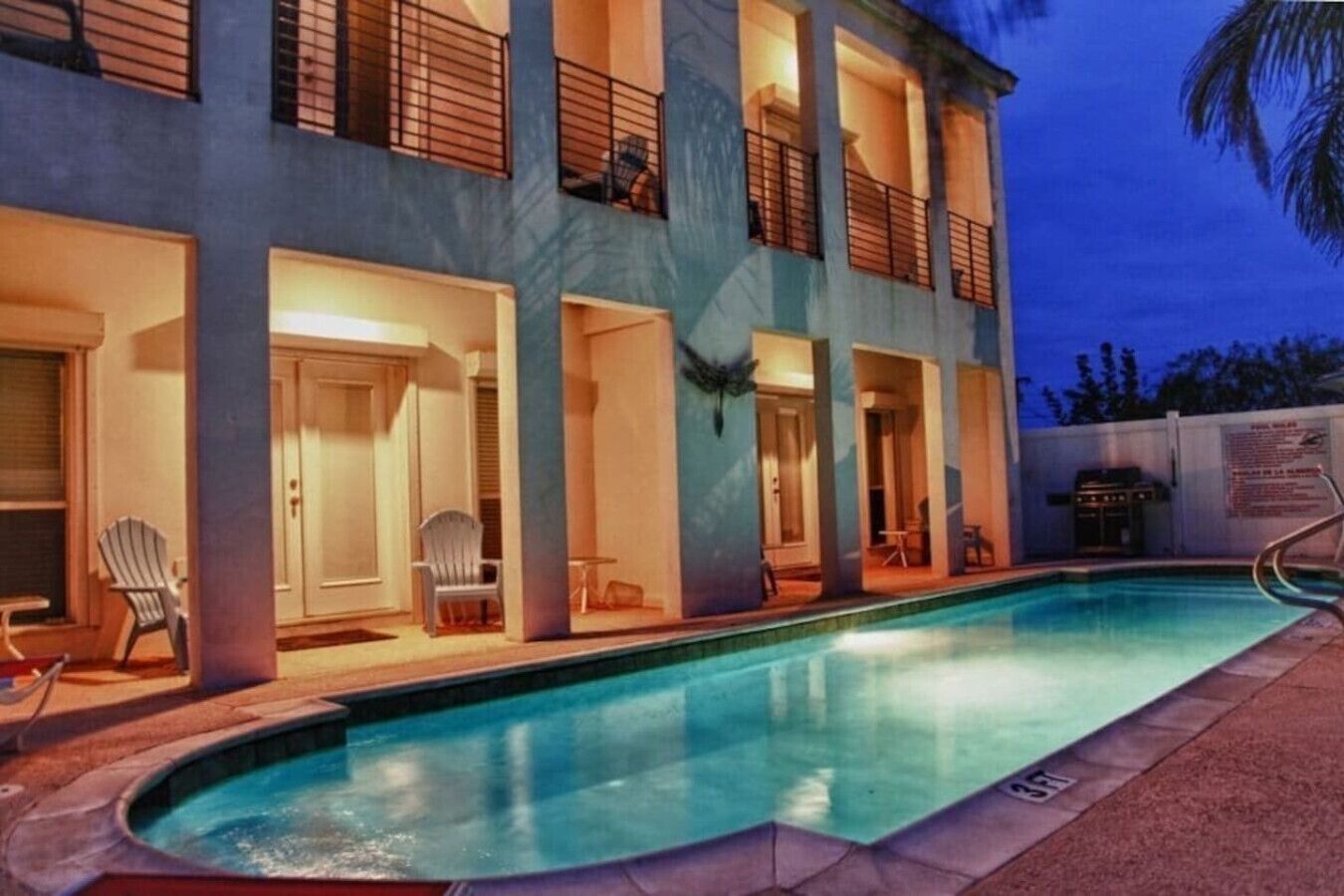 A hotel with a swimming pool, multiple balconies, and outdoor seating areas.
