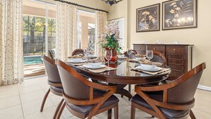 A dining room with a round table set for four, surrounded by wooden chairs. - Luxury 5 Star Vacation Villa- Free WiFi & Long Distance (Kissimmee)