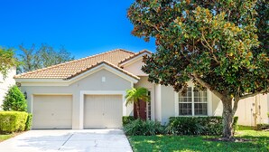 A single-story house with a garage, a front lawn, and a tree. - Luxury 5 Star Vacation Villa- Free WiFi & Long Distance (Kissimmee)