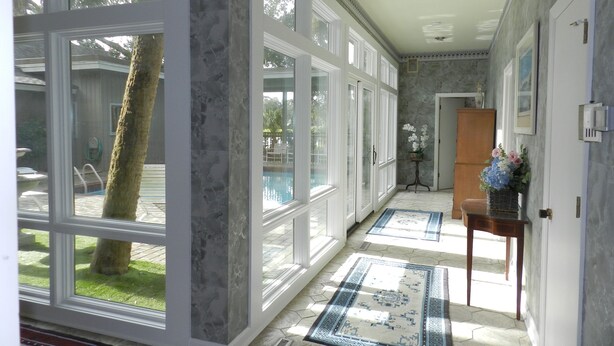 A spacious hallway with large windows, a pool view, and a door leading to a room. - Rates Jan through mid March 2027 are reduced for longer stays. (Hilton Head Island)