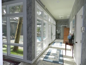 A hallway with large windows, a pool, and a door leading to another room. - Rates Jan through mid March 2027 are reduced for longer stays. (Hilton Head Island)