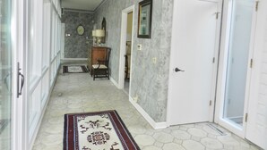 A hallway with a patterned rug, a wooden chair, a lamp, and a clock on the wall. - Rates Jan through mid March 2027 are reduced for longer stays. (Hilton Head Island)