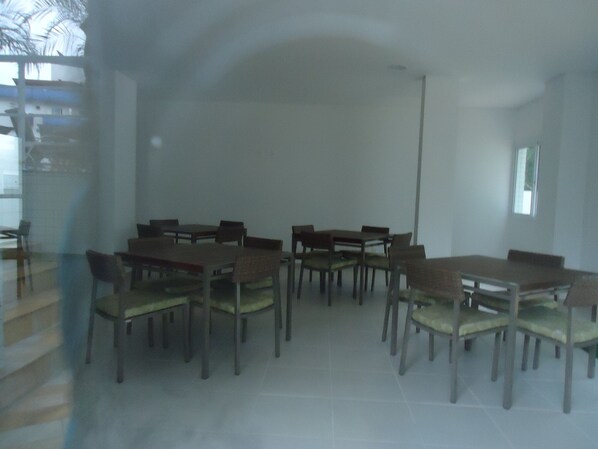 Un espace repas comprenant plusieurs tables et chaises, un escalier et une fenêtre.