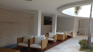 Et moderne loungeområde med fletningsmøbler og flisegulv, komplet med et buet loft og udsigt til et palmetræ.