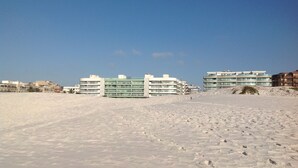 En sandstrand med moderne bygninger i baggrunden.