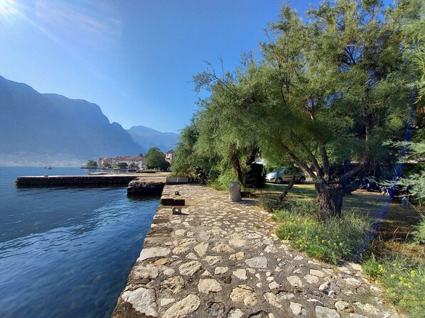 A stone pathway along a lake with a view of mountains in the background.