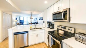 A modern kitchen with white cabinetry, a built-in dishwasher, a stove, a microwave, and a toaster.